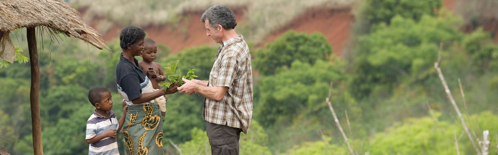 笑顔で植物を手渡しするアフリカ系母子と白人男性